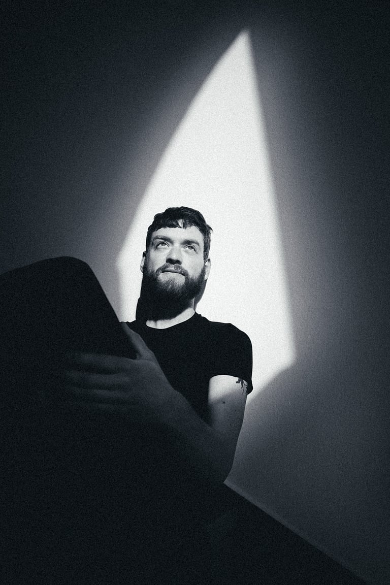 Ein Schwarz-Weiß-Porträt eines jungen Mannes, der auf einer Treppe sitzt.