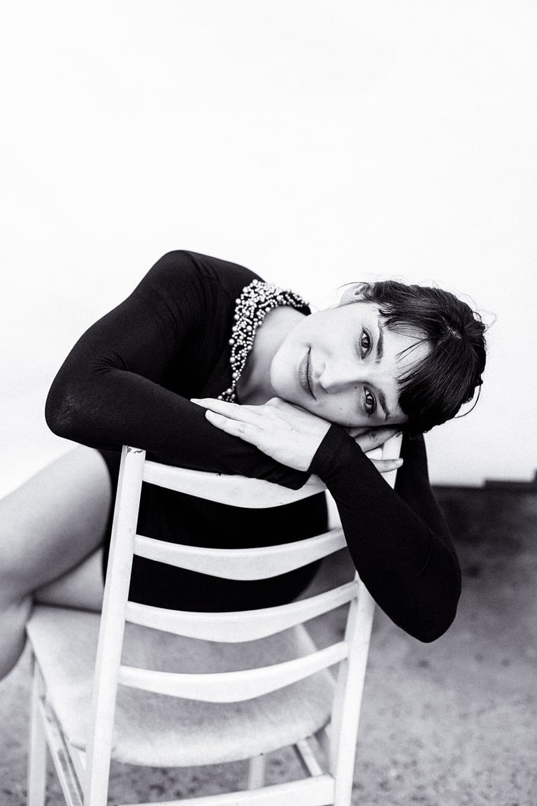 Woman wearing a black dress sitting on a chair.
