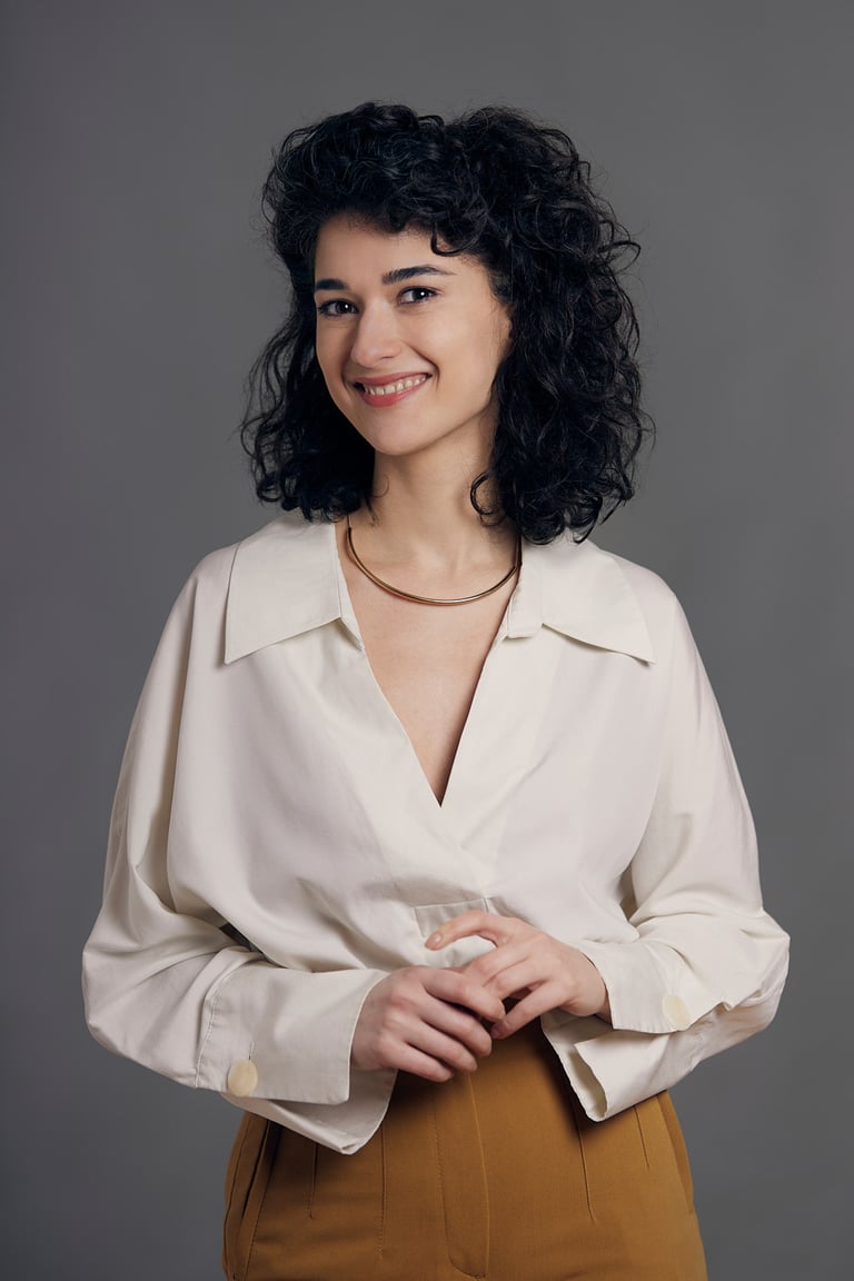 A young woman with curly hair smiling into the camera.