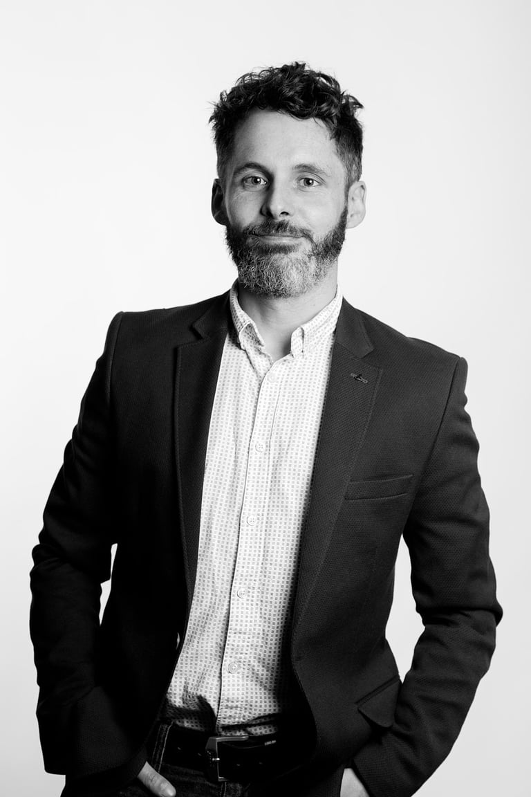 A man in a suit jacket smiling during a studio shoot.