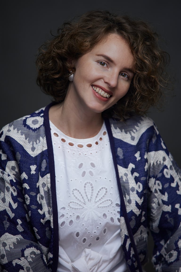 A portrait of a woman wearing a folk inspired white shirt.