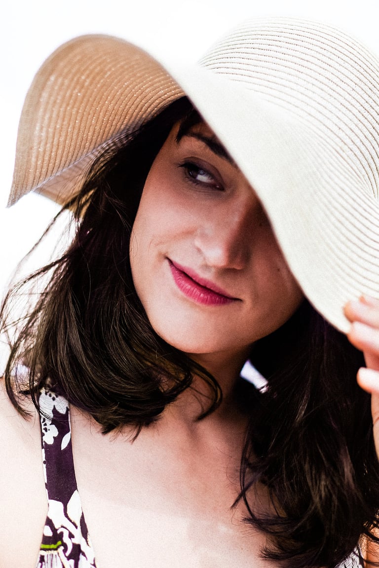 A headshot of an actress in a straw hat looking to the side.