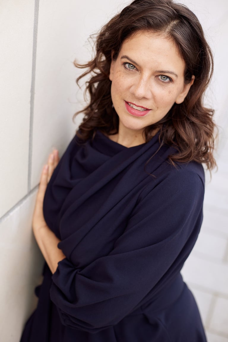 A woman next to a wall looking into the camera.