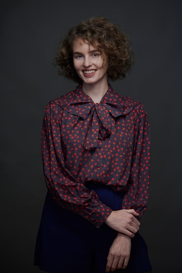 A young woman in a polka dorr blouse with a bow.