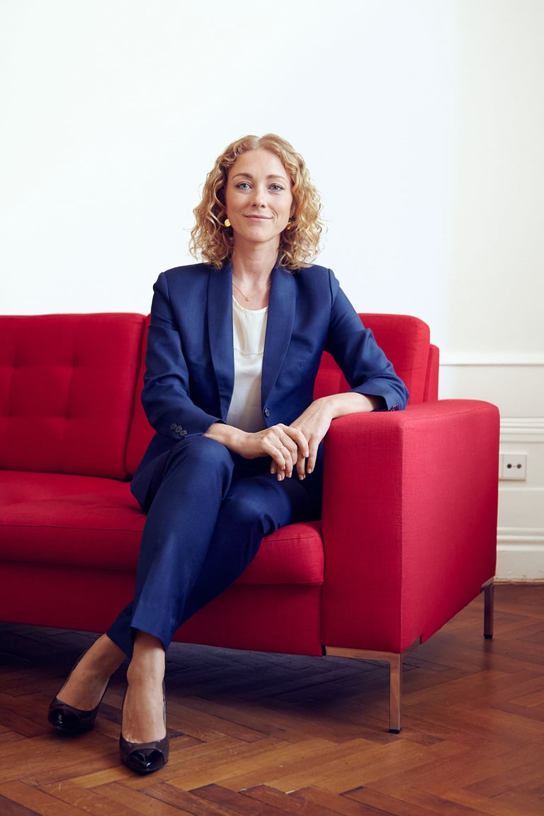 Business woman seating on a red couch.