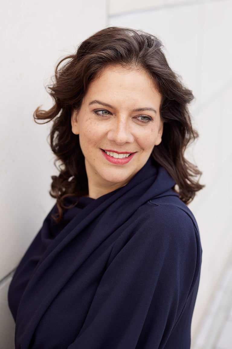 A woman wearing red lipstick smiling looking over her shoulder.