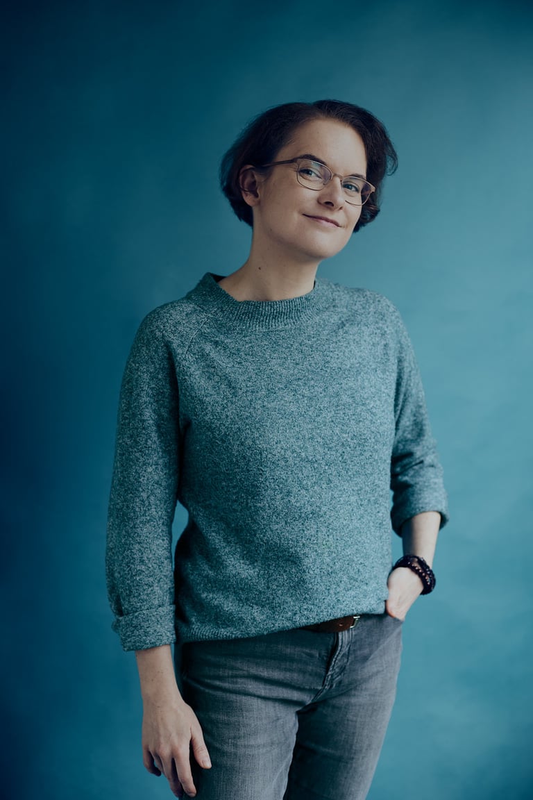 Woman standing in a studio with a blue background.