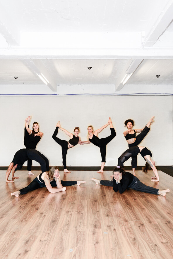 Acht mensen voeren verschillende acrobatische poses uit, waaronder brug, split en handstand in Gent