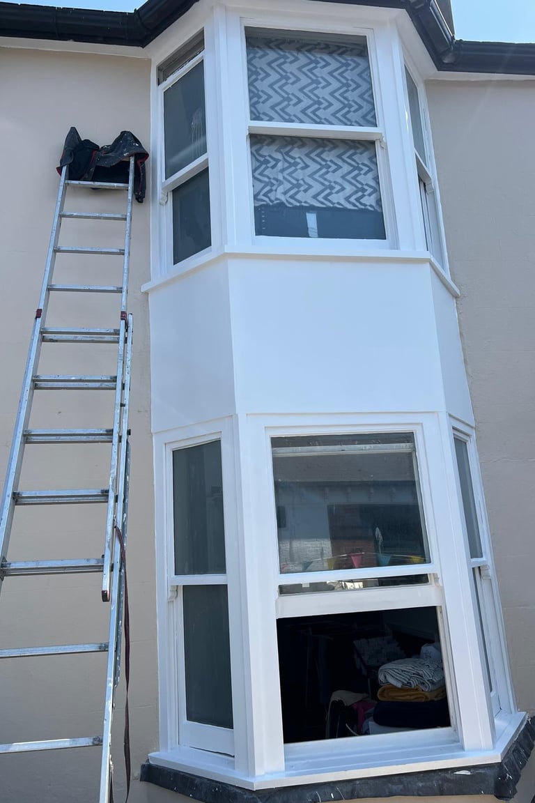Professional exterior house painting of white bay windows by Diamond Decor in Sussex.