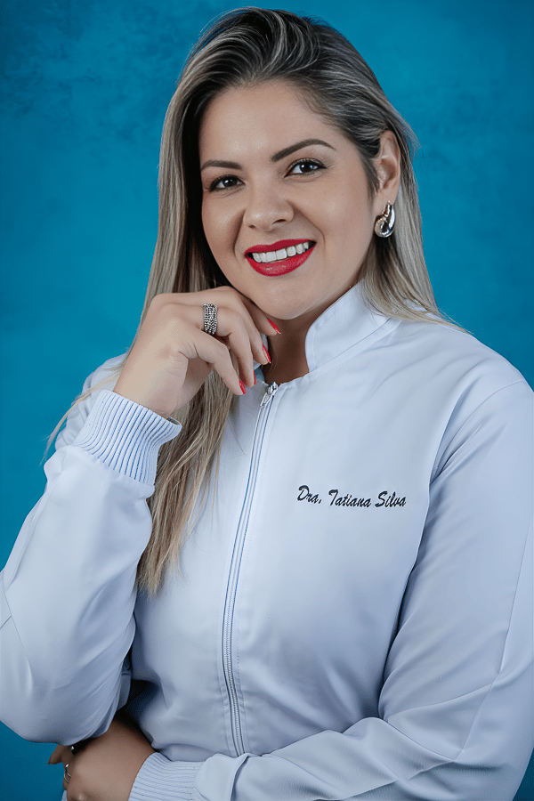 mulher loira médica com jaleco branco posando com a mão no queixo e sorrindo, posando em fundo azul