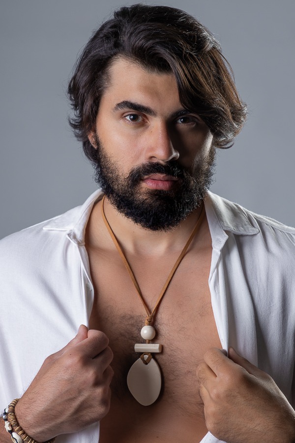 Modelo masculino roupa branco, camisa aberta, cabelos longos e barba em ensaio fotográfico estúdio