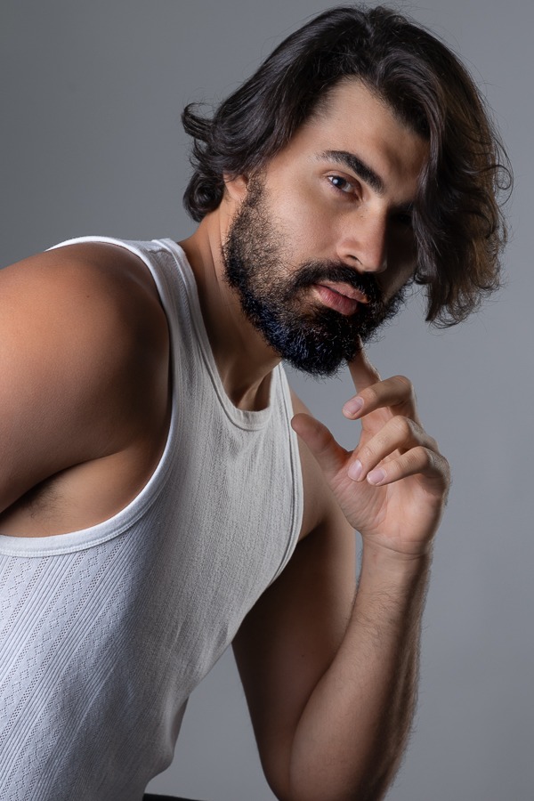 Modelo em pose de perfil , cabelos longos e barba, pose em book no estúdio