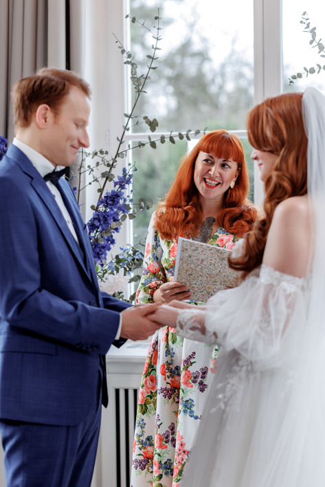 Traurednerin blickt während des Ja Worts zum Bräutigam. er hält die Hände der Braut