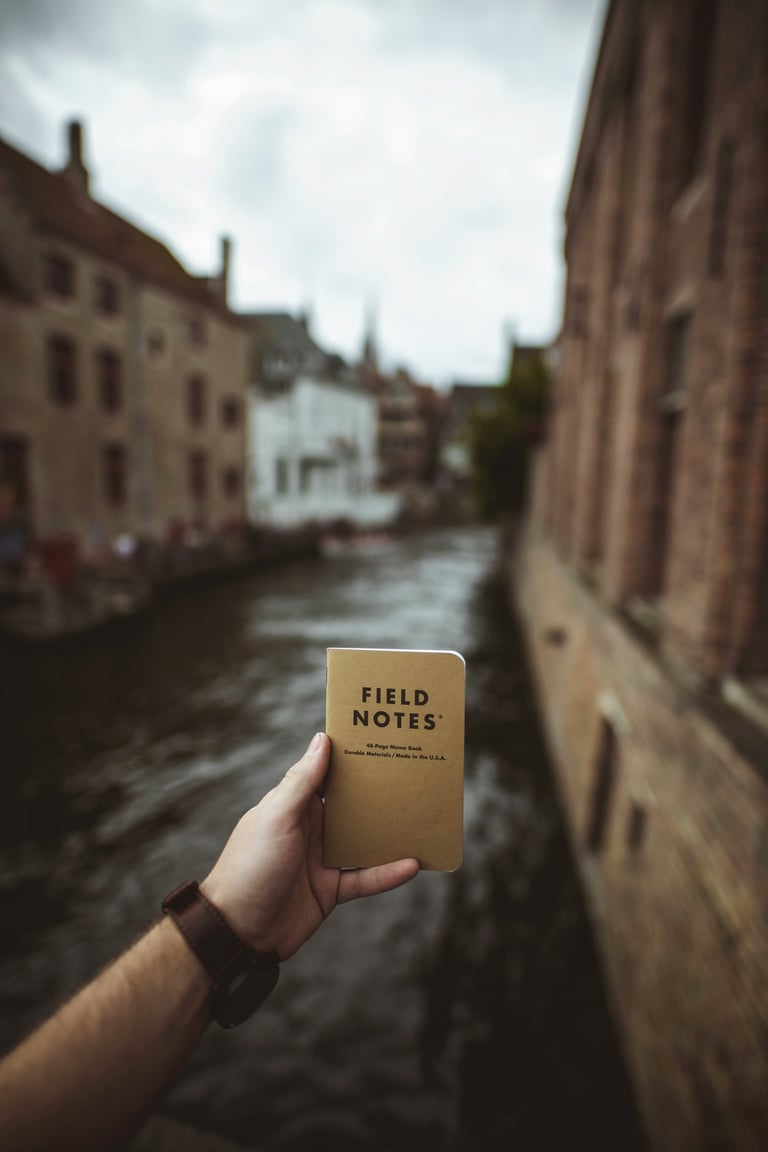 Journal titled "Field Notes" held up in front of a Canal; Photo by Vadim Sadovski on Unsplash