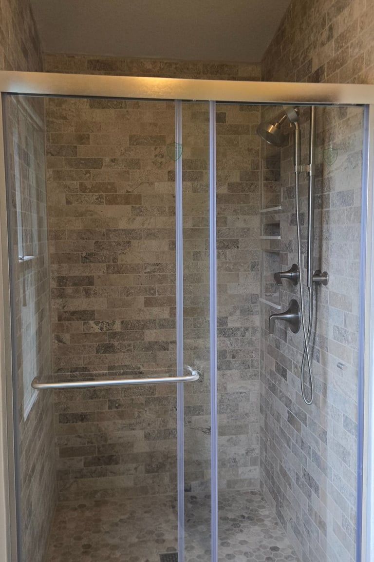 Modern walk-in shower featuring natural stone subway tile walls and a sliding glass door.