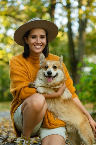 Mujer feliz abranzando a corgi en el parque