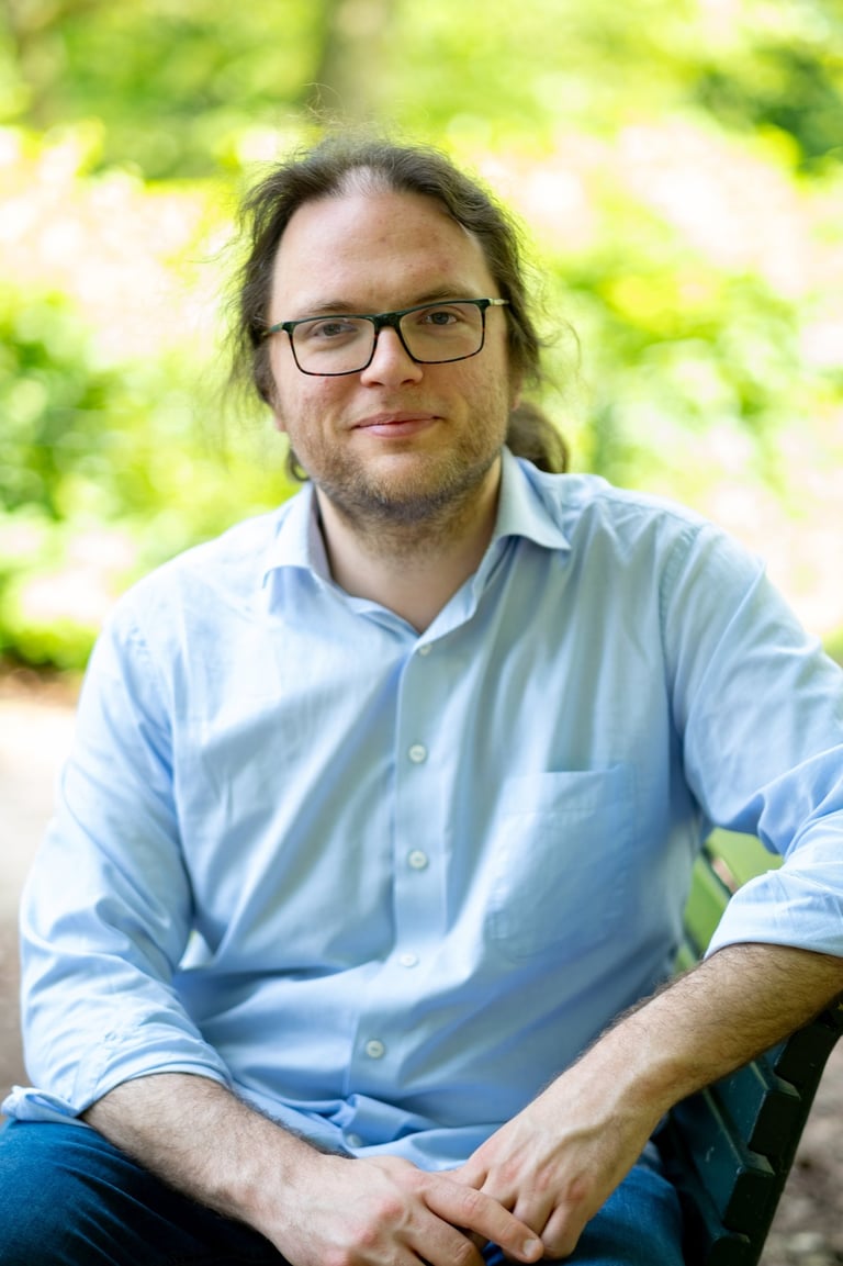 Jelle Dehaen, een therapeut met wat langer haar en een bril. Hij is rustig en vertrouwensvol.