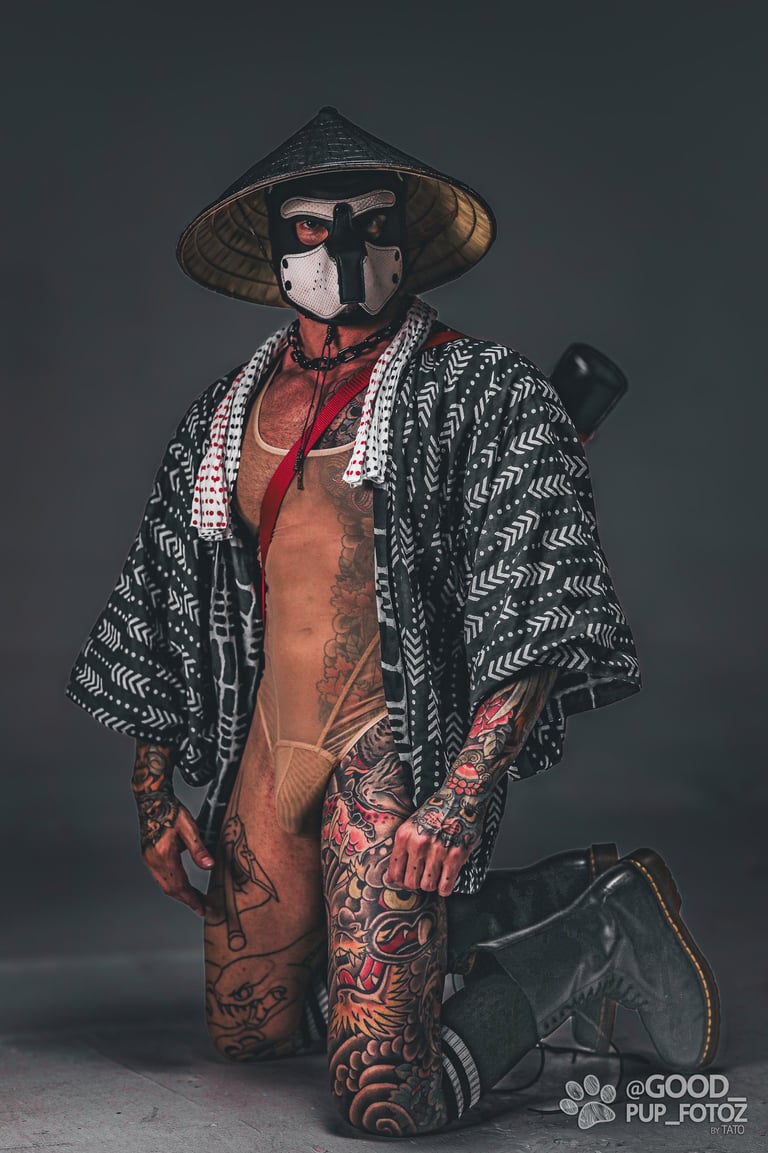 Tattooed man in a pup mask, Haori Jacket, and a dǒulì conical hat.