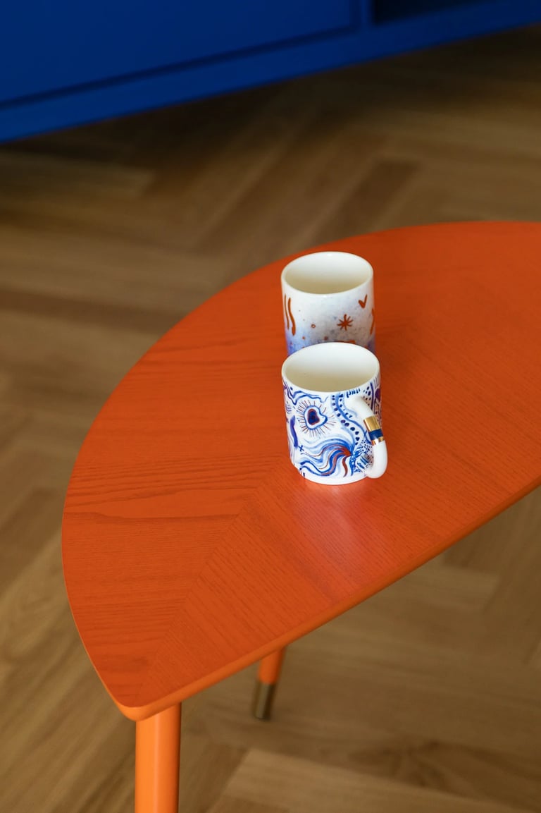 Stylizacja wnętrza: eklektyczny salon, pomarańczowy stolik i sztuka.