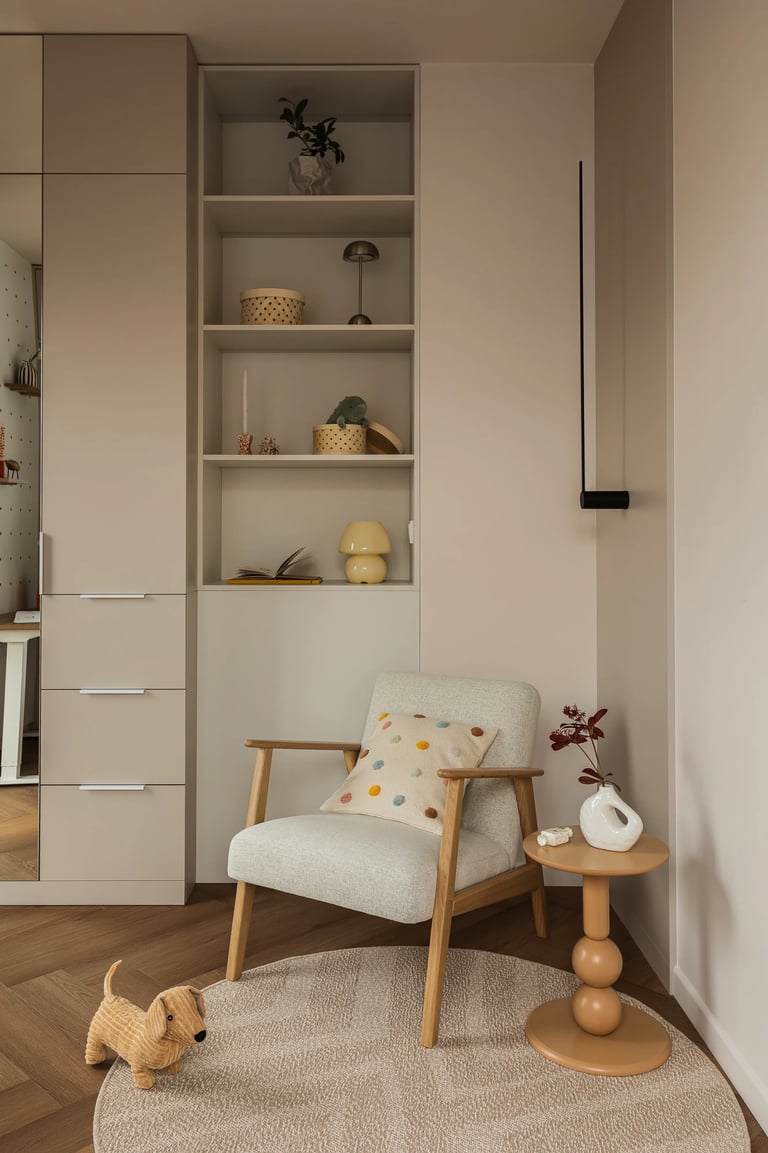 Kącik wypoczynkowy, jasny fotel, stolik i ścianka dekoracyjna pegboard.