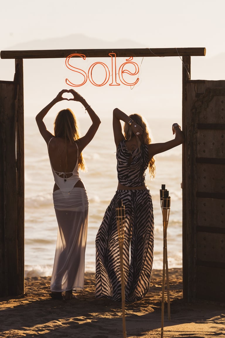 Elegant guests arriving at the iconic SOLÉ wooden gate, Trocadero Zanzibar Marbella beachfront.