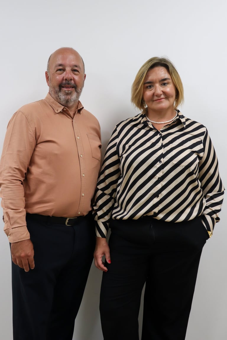 Professional portrait of male and female business partners standing together in formal attire against a white background.