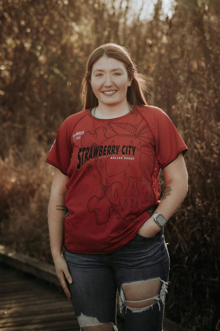 a brown haired, brown eyed woman in a red shirt and ripped jeans