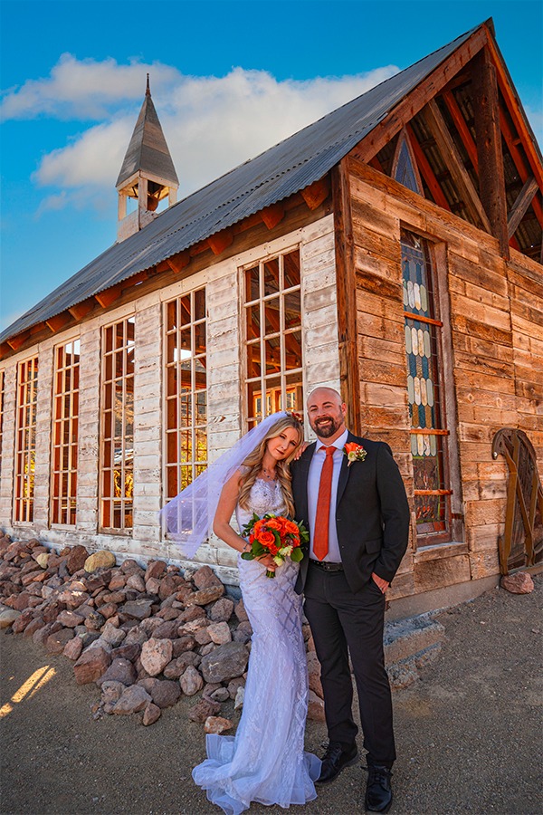 a bride and groom standing in front of a church