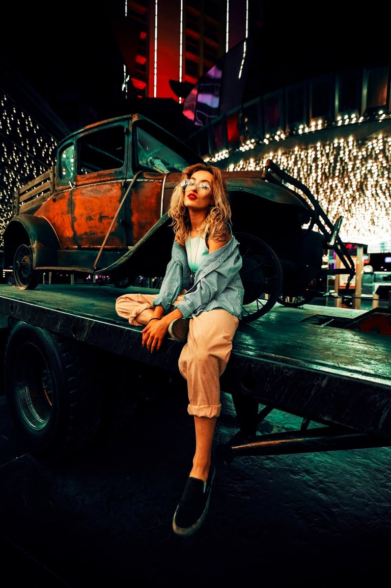 a woman sitting on a truck bed with a car in the background