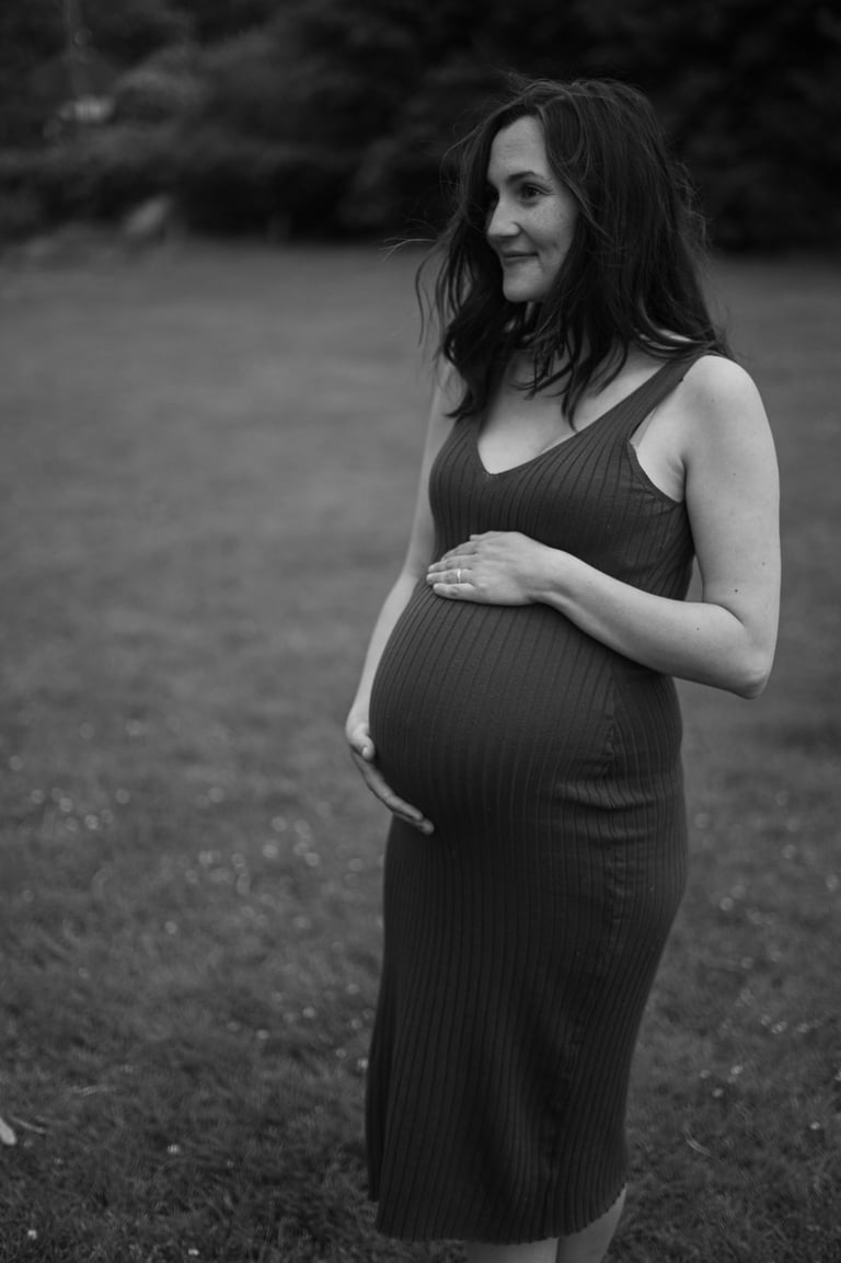 black and white image of pregnant woman holding her baby