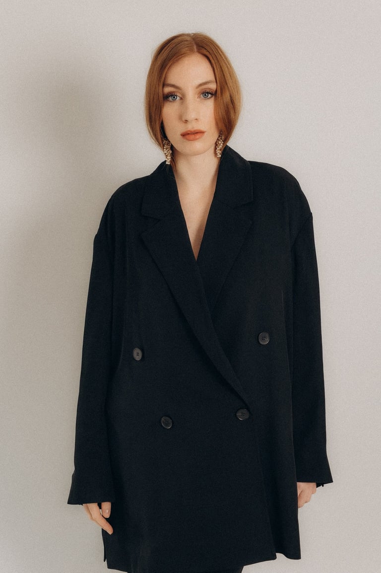 a woman in a black coat and white pants