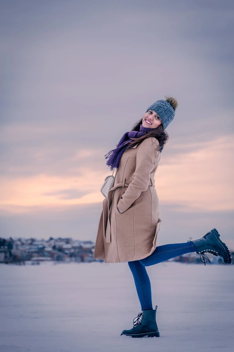 a woman in a coat and hat standing in the snow