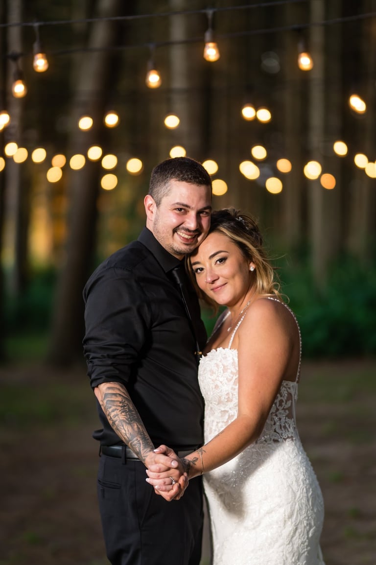 a bride and groom standing in front of a string light