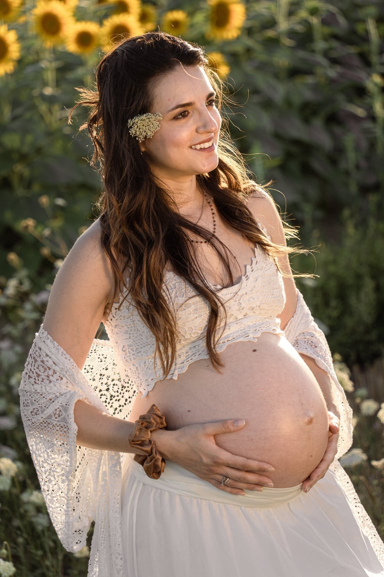 a pregnant woman in a white dress and sunflowers