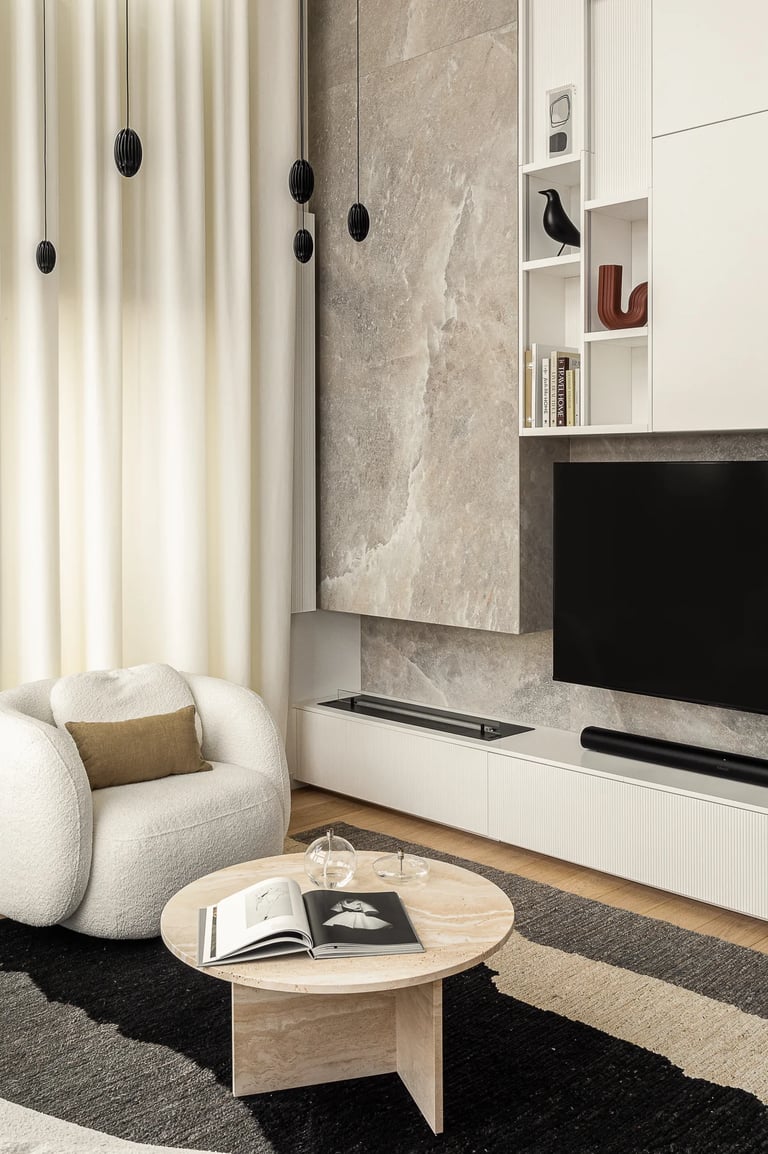 Salon z brązową sofą Togo, fotelem boucle i kamienną ścianą TV.