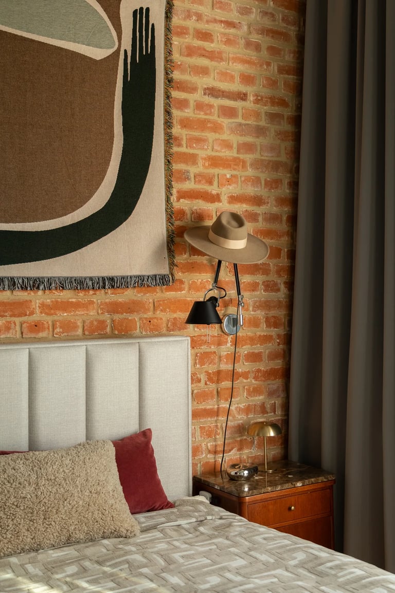 Ceglana ściana w sypialni loft, czarny kinkiet i dekoracje.