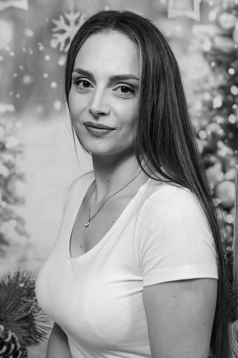 Black and white portrait of a woman with long hair and a necklace against a festive holiday background.