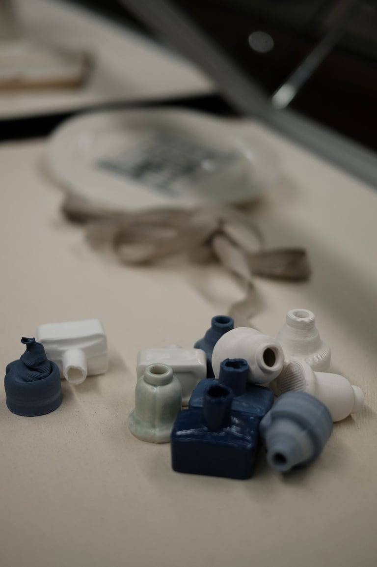 A group of small porcelain ink bottles,, in white and blue, are tumbled together in a display case