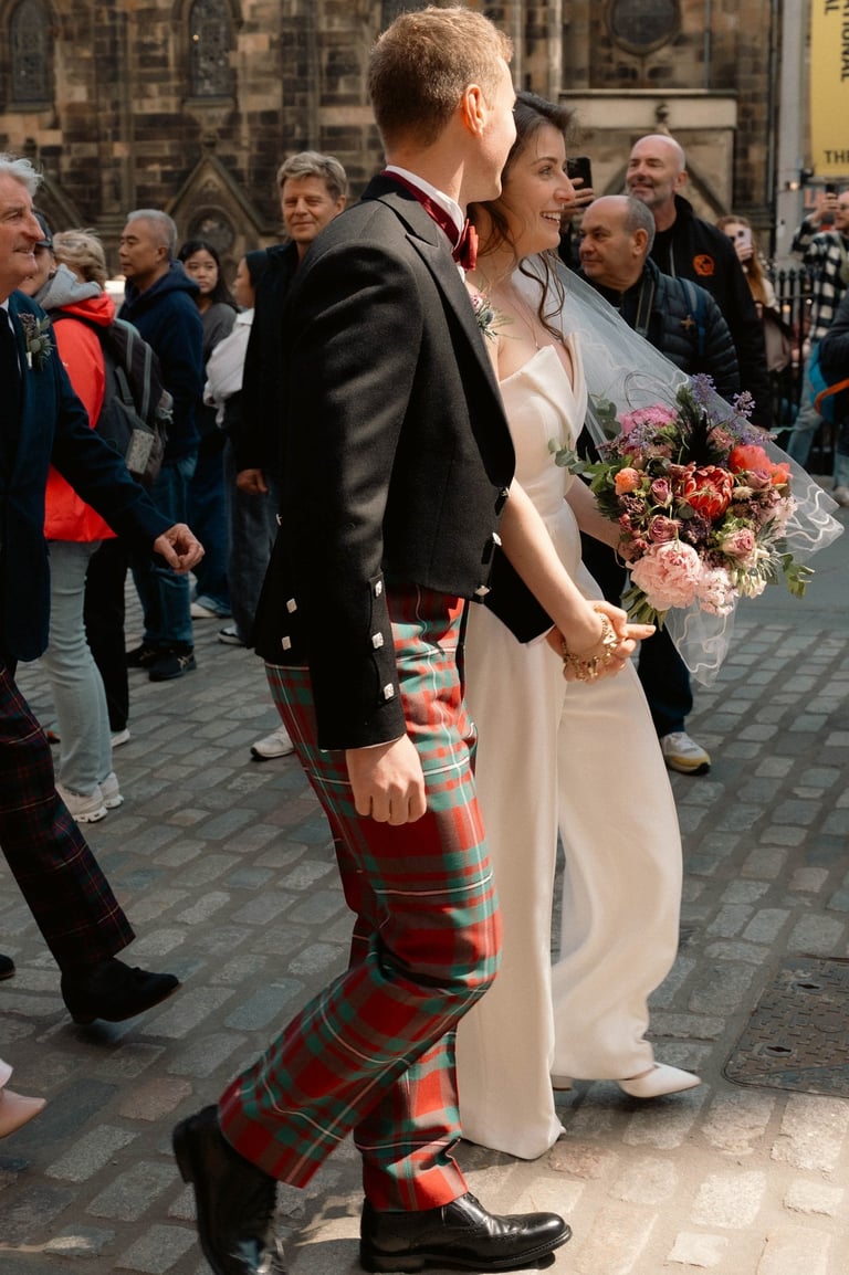 a man and woman in plaidered kilts walking down a street