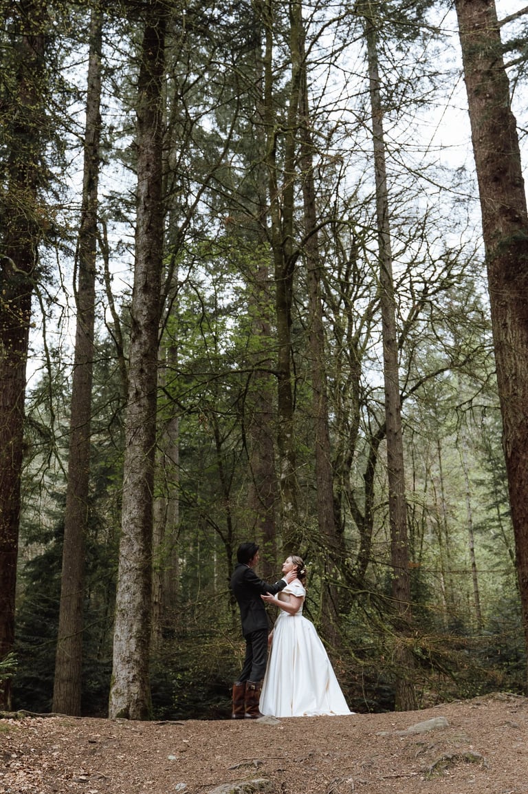 a bride and groom standing in a forest
