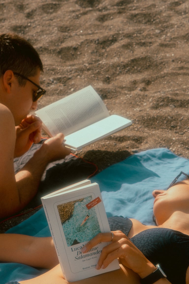 a man and woman reading a book on a blanket