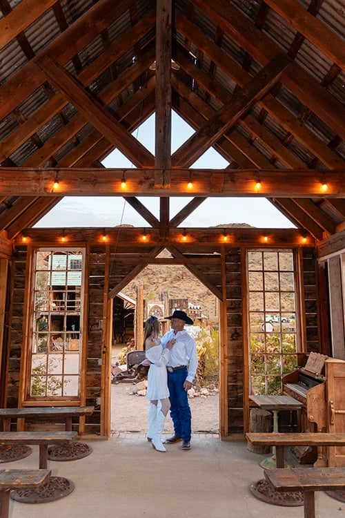 a man and woman standing in a barn like structure