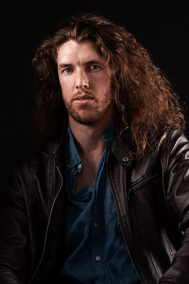 a man with long hair and a beard wearing a leather jacket