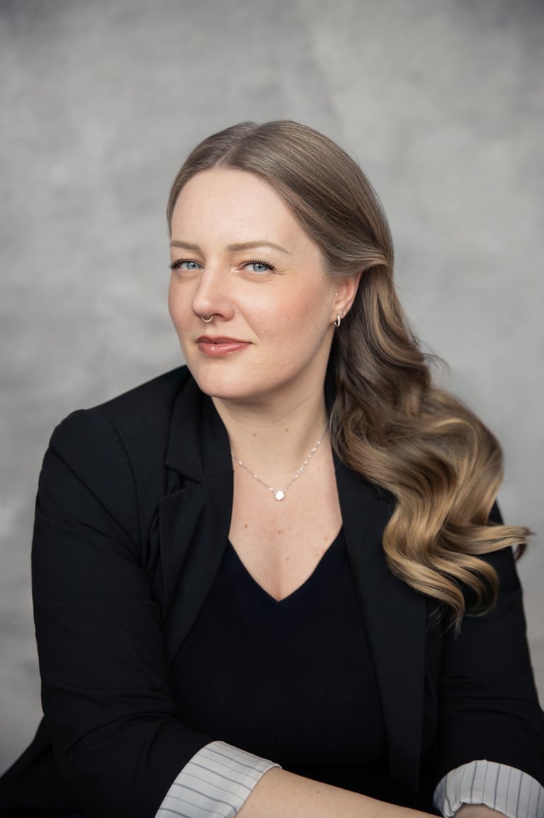 Professional corporate headshot of a woman with blonde wavy hair wearing a black blazer.