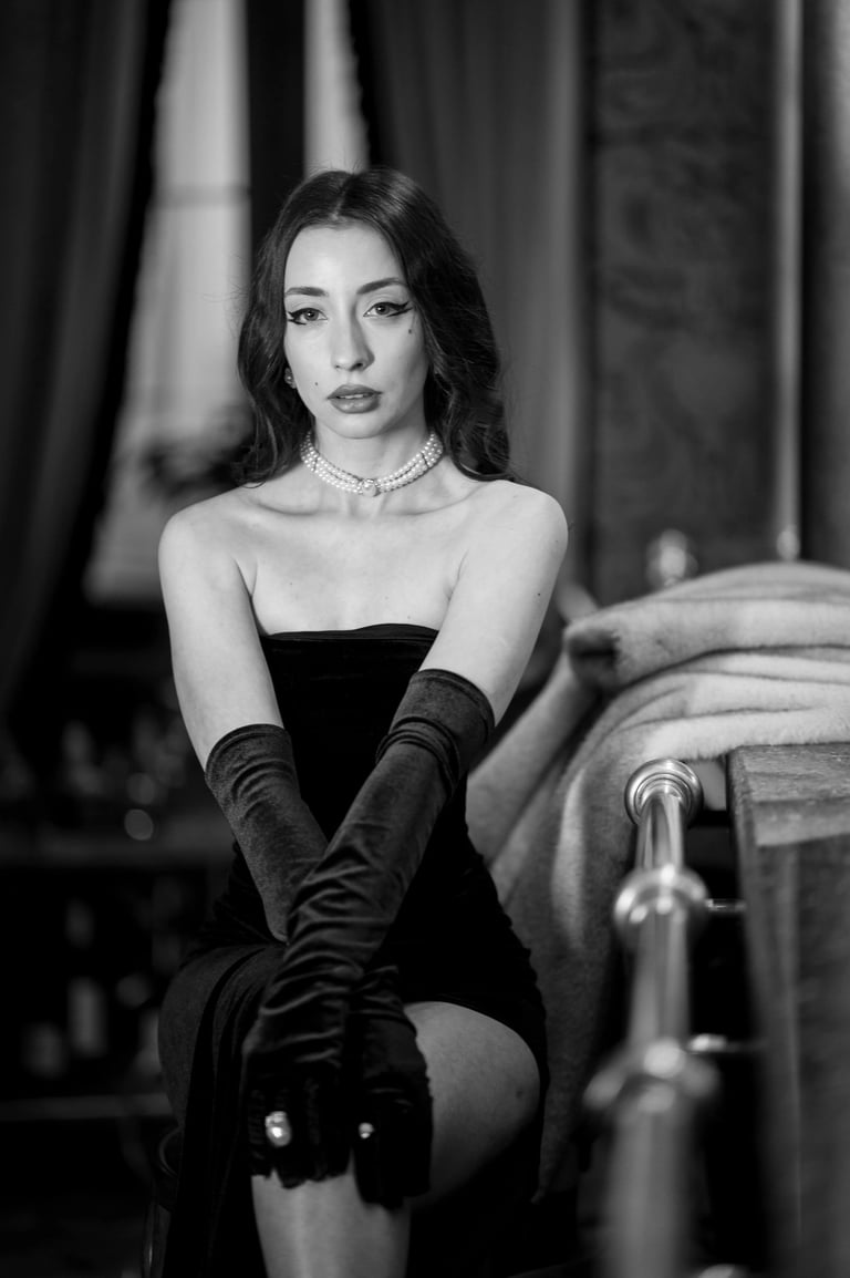 Old hollywod style portrait photo ow a woman with pearls and black dress sitting at the bar