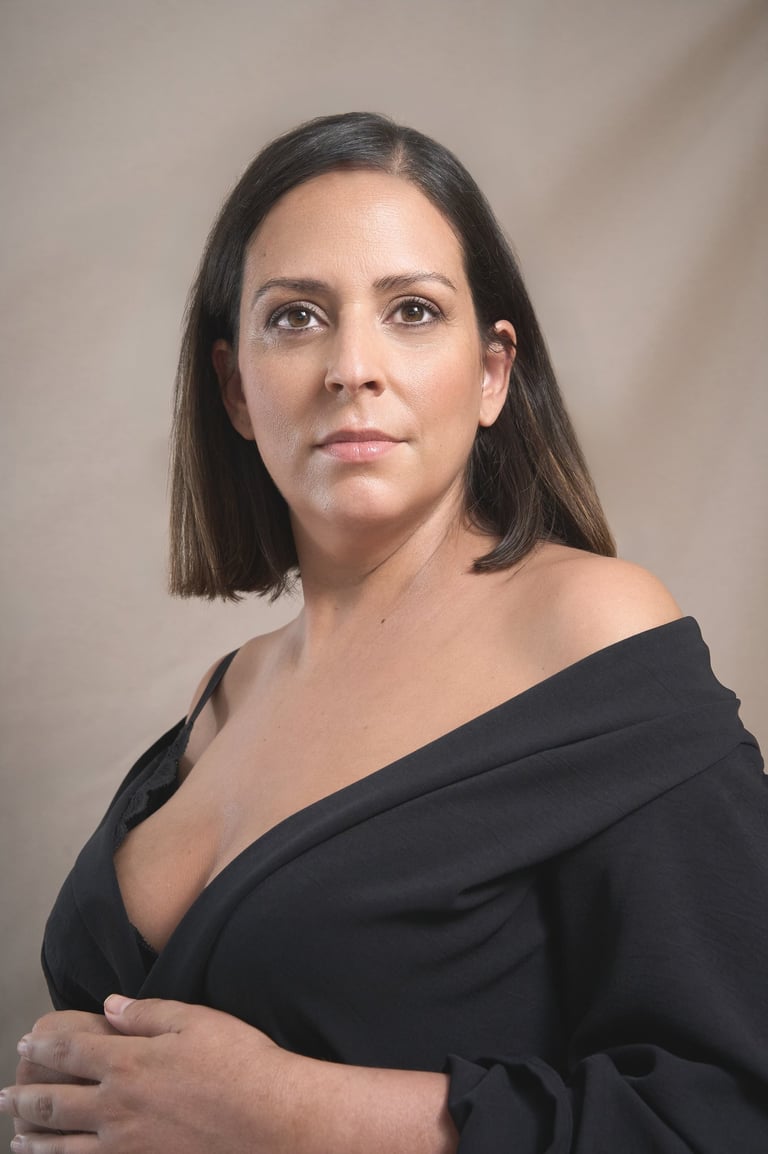 Professional portrait of a woman with short brown hair wearing a black off-the-shoulder top.