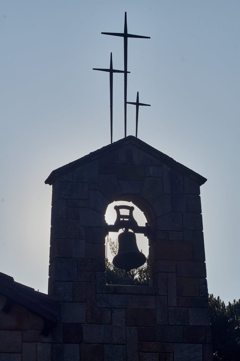 Campanario de piedra con tres cruces al amanecer.