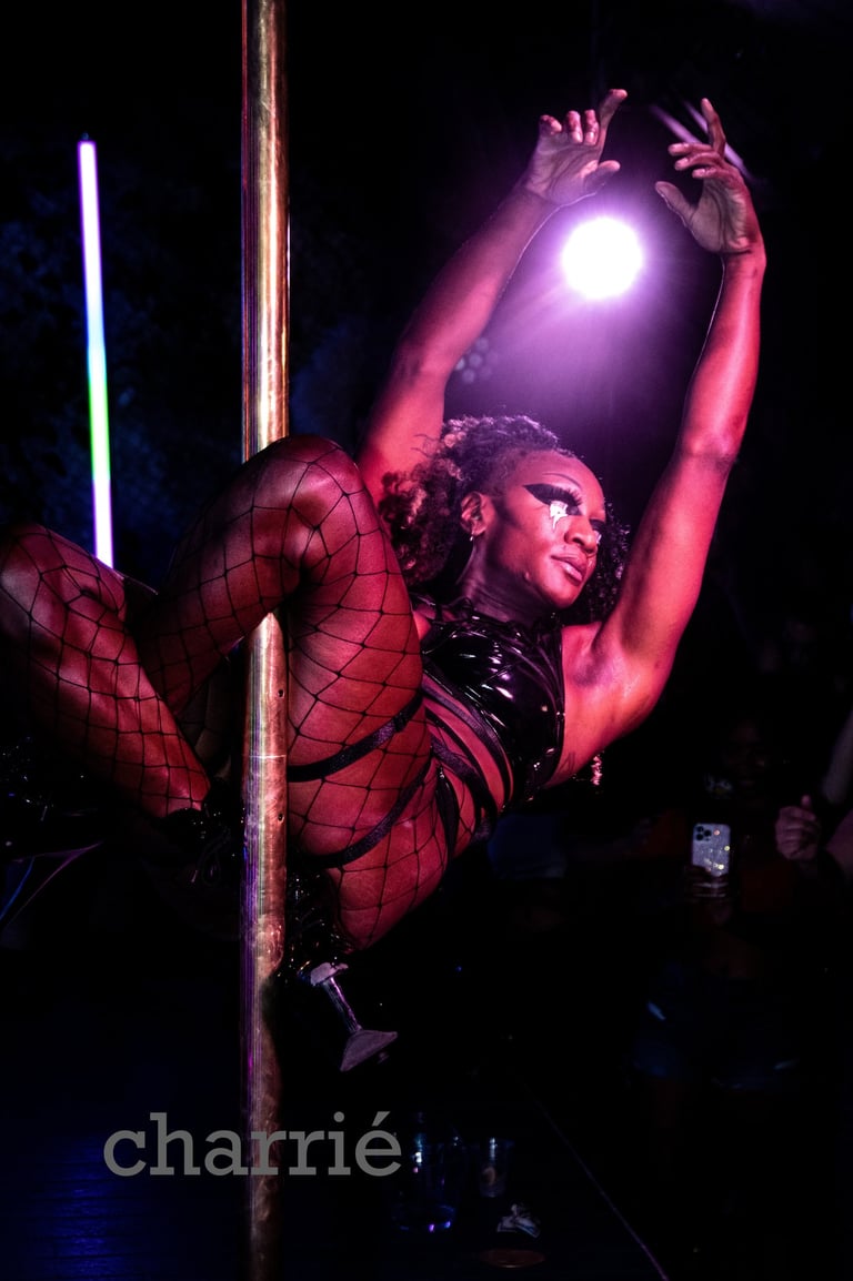 black woman suspended by mesh cover legs on pole, arms outstretched gracefully backlit by spotlight
