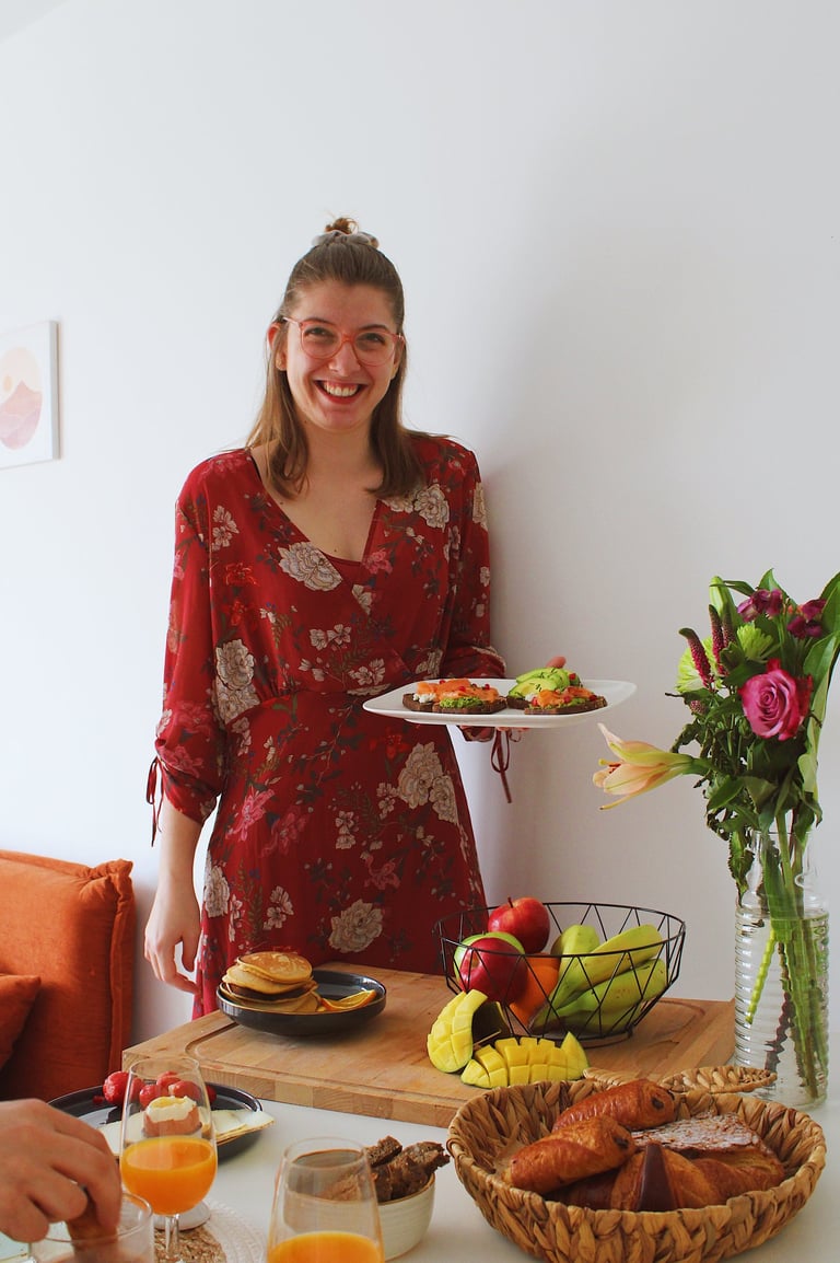 Amélie Biron, souriante, présentant un brunch appétissant, plein de couleurs et de saveurs. 