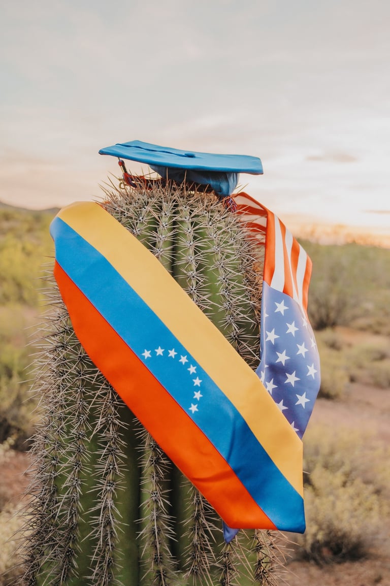 A saguaro cactus wearing a blue graduation cap with Venezuelan and American flag stoles in the desert.